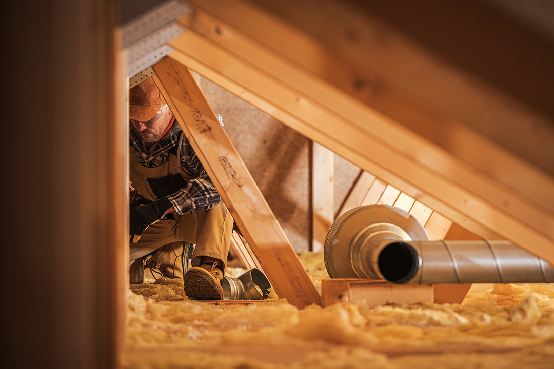 Worker inspecting attic ventilation and insulation