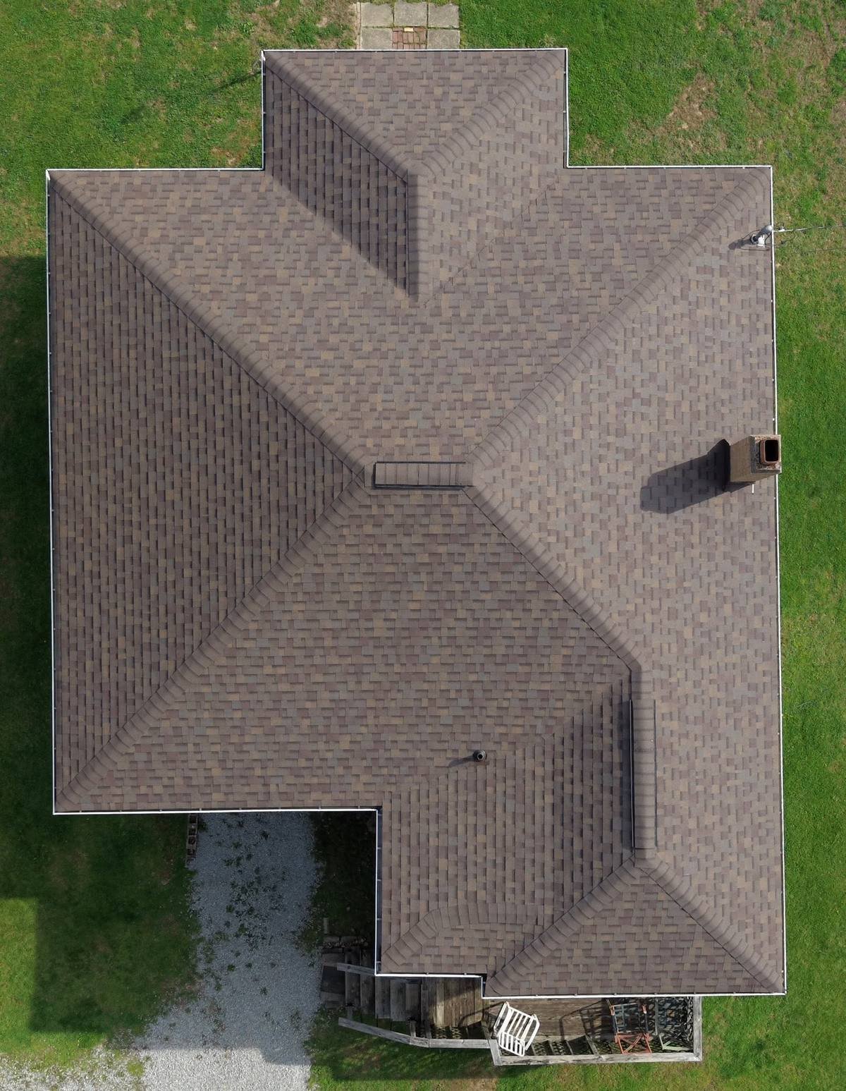 Older red-brick house with a chimney and a gray composition shingle roof, showing what is composition roofing material